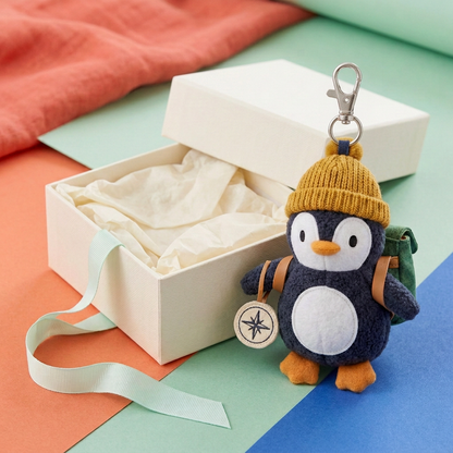 Explorer Penguin with attached clasp beside open unbranded ivory gift box